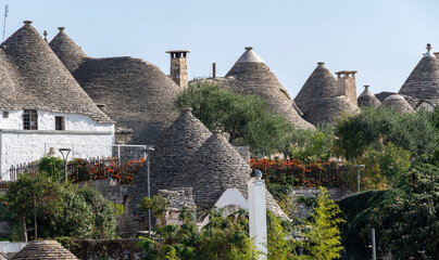 Conical roofs of the Trulli among green vegetation in the historic center of Alberobello in Puglia