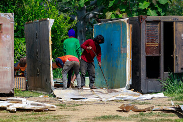 Construction Workers Dismantling and Recycling Old Container Panels Outdoors