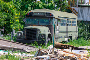 Abandoned Vintage School Bus Painted in Military Camouflage, Junkyard or Glamping Spot