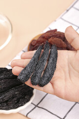 Hand Holding Dried Vanilla Beans with Spices and Raisins for Cooking and Baking © NguyenThi