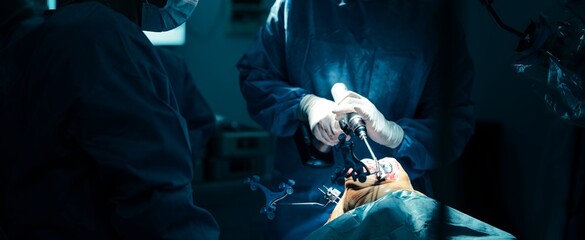 In operating room, surgeons wearing blue scrubs perform a knee replacement. Robotic arm assists with precise bone resection, ensuring alignment and optimal outcome for the patient