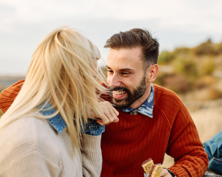 Hiking couple enjoys nature taking a break with water bottle or hot drink tea at the table in a lush forest during a sunny day
