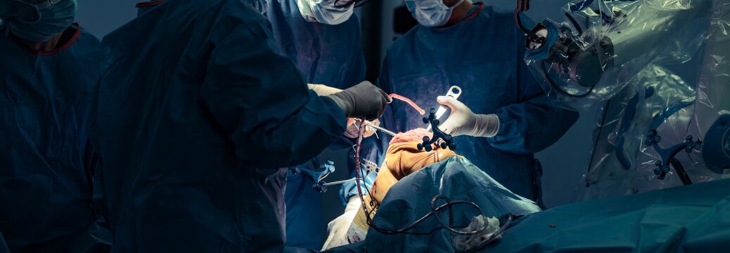 Surgeons in scrubs use robotic assistance to perform a knee replacement. Advanced technology enables personalized joint alignment. The procedure takes place in a sterile operating room