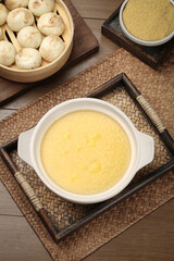 Healthy millet porridge breakfast with steamed buns and grains on wooden table