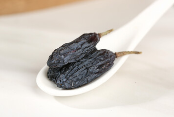 Turpan Black Dried Grapes from Xinjiang China on White Spoon - Traditional Asian Dried Fruit Snack