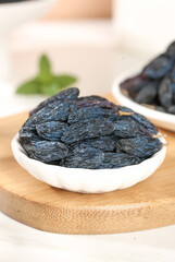 Turpan Black Dried Grapes from Xinjiang China in Bowl with Mint on Wooden Board