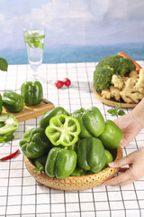 Fresh Green Bell Peppers Collection in Basket with Variety of Vegetables and Ocean Background