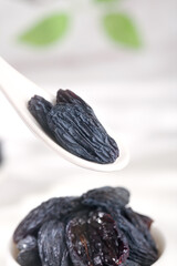 Black Dried Grapes from Xinjiang Tulufan China on White Ceramic Spoons Traditional Asian Dried Fruit Food Photography