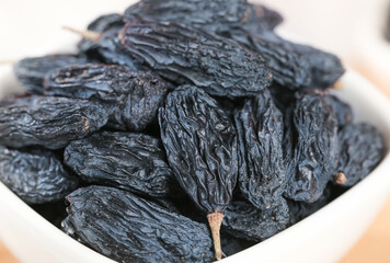 Black Dried Grapes from Turpan Xinjiang China in White Bowl - Traditional Dehydrated Fruit Snack