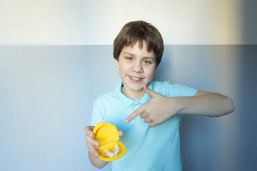 Young boy proudly showing off a yellow toy while smiling against a light background