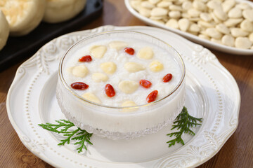 Traditional almond porridge with goji berries and nuts in elegant white ceramic bowl