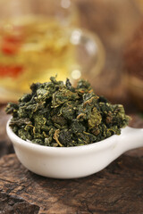 Dried Mulberry Leaves in Bowl for Healthy Herbal Tea Recipe on Rustic Wood Background