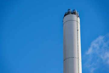 Industrial chimney of Flensburg power plant rising against clear blue sky on sunny day