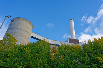 Flensburg power plant chimney behind green trees symbolizing balance of nature and industry