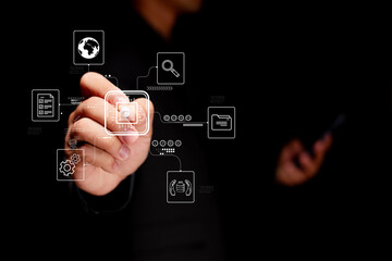 A person interacts with digital icons, showcasing technology and connectivity in a dark environment, highlighting modern advancements.