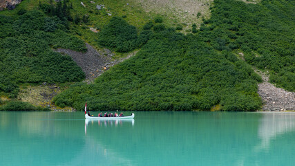 Panoramic image of a group of tourists in a canoe with a Canadian flag on Lake Louise in Banff National Park
