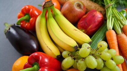 Fresh fruits and vegetables offering diverse colors and textures, promoting healthy eating, nutrition, and a balanced diet with raw food ingredients on a gray background