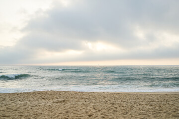 A beach with a cloudy sky in the background The sky is overcast and the ocean is calm