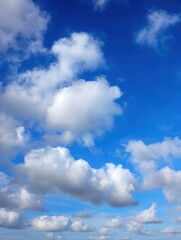 Obraz premium Bright Blue Sky Filled with White Cumulus Clouds on a Sunny Day Overhead View from Ground Level