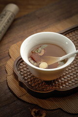Traditional Chinese Medicine Herbal Tea with Licorice and Astragalus in White Cup on Bamboo Mat