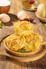 Crispy Potato Nest Pastries on Wooden Plate - Traditional Fried Cuisine with Fresh Herbs and Kitchen Ingredients