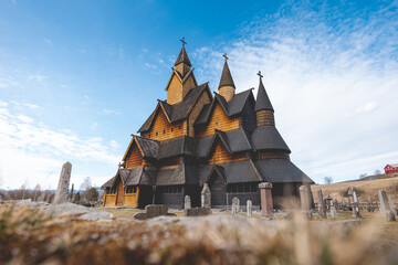 Heddal Stave Church in Norway stands under a bright blue sky, its intricate wooden towers glowing warmly a masterpiece of medieval Nordic architecture