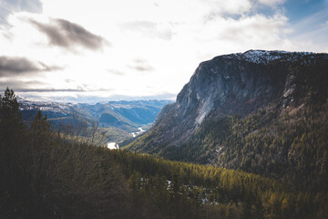 Epic mountain cliffs overlooking green valleys and snowy ridges in Norway. A cinematic view of Nordic wilderness and powerful nature