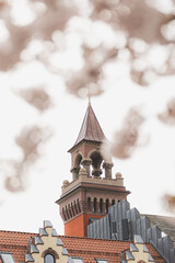 Architectural detail of historic tower in Kristiansand, Norway, framed by blooming cherry trees. Blend of culture, history, and nature in Nordic springtime