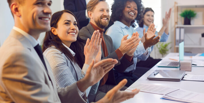 Group of happy business people in an office meeting event, applauding and celebrating success together. Crowd showing teamwork and companionship in a collaborative business environment.