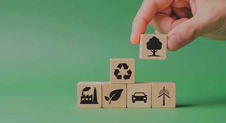Hand stacking wooden blocks with environmental icons representing sustainability and eco-friendly practices.