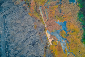 aerial post eruption moss and meltwater, regrowing orange and green vegetation punctuated by shallow pools
