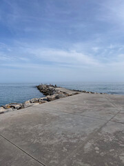 A pier made of large, warm-toned concrete slabs, photographed in beautiful natural gray-blue tones. Spain, 2022.