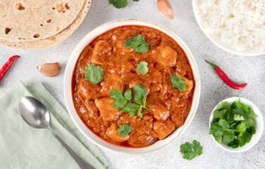 Indian butter chicken with rice, chapatti and cilantro on a white background. Top view. Indian food.