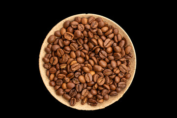 Roasted coffee beans in a ceramic saucer on a black background, top view.