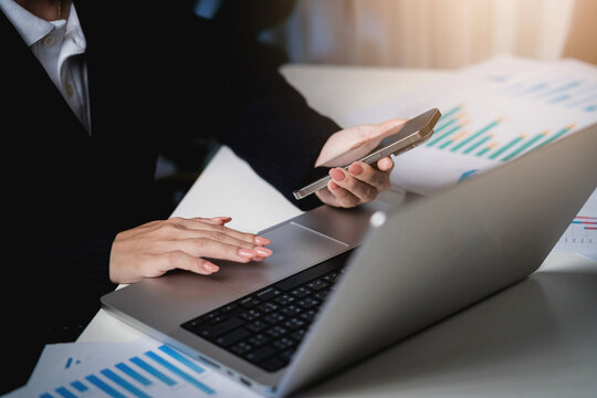 A woman is using a laptop and a cell phone - Powered by Adobe