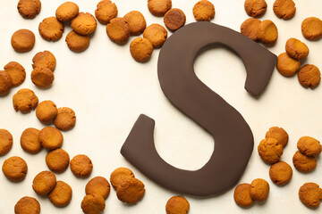 Sinterklaas (Saint Nicholas) Day. Chocolate letter S and kruidnoten cookies on light background,...
