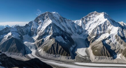 Snowy mountain peaks reach up to a clear, blue sky. Glacial valleys below