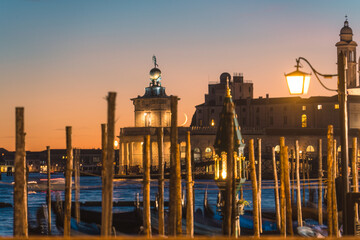 Basilica di Santa Maria della Salute with gondola pier and illuminated street lamp by Grand Canal in Venice, Italy © Mumemories