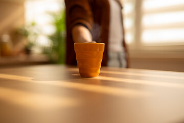 Person offering warm drink on sunlit table