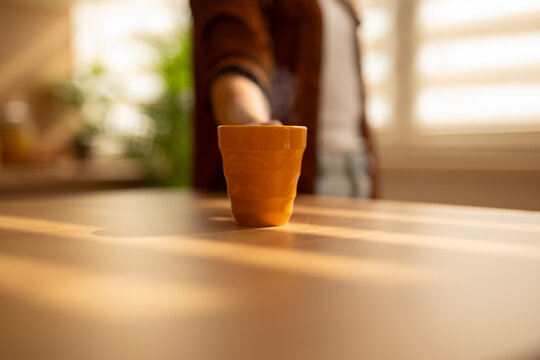 Person offering warm drink on sunlit table