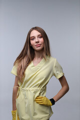 Young caucasian female in yellow uniform with gloves posing confidently