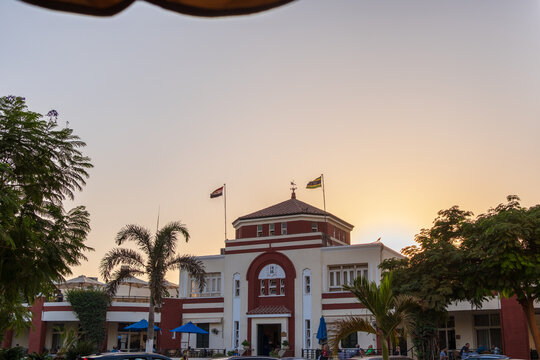View of the historic Lido building of Gezira Club and lush greenery casting shadows in the warm light, Zamalek, Cairo Governorate, Egypt.