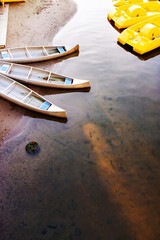 Canoes and yellow pedal boats on calm Baltic shoreline