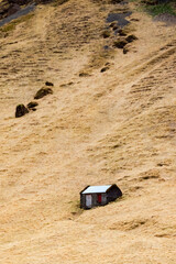 Small isolated hut on golden hillside in Iceland