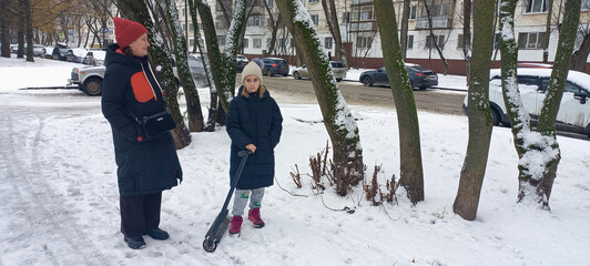 Adult woman and child standing in snowy park on winter day  