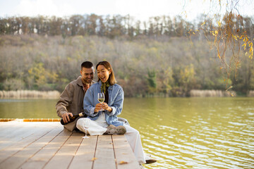 Naklejka premium Couple enjoys a romantic moment by the serene lake during a sunny afternoon
