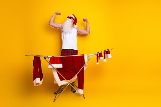 Santa flexes in a home scene as a grandpa man wears pajama and irons Christmas laundry for a festive holiday vibe