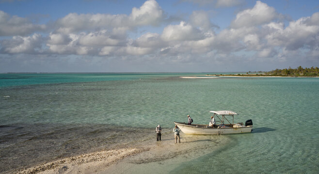 ly fisherman preparing to wade the shallow tropical flats beside a skiff on Kiritimati (Christmas Island), Kiribati. The crystal-clear turquoise waters and pristine Pacific coastline make this world-f