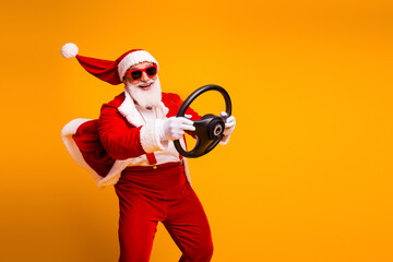 Santa in a bright red suit drives a steering wheel with funny charm for Christmas campaigns and...