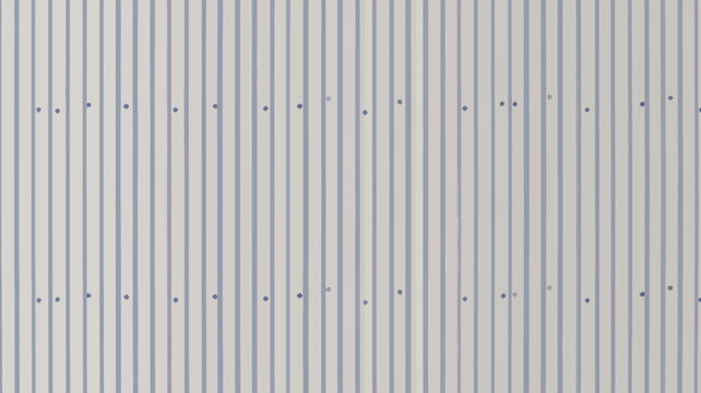 A close up of a white metal corrugated wall with fasteners evenly spaced in a repeating pattern
